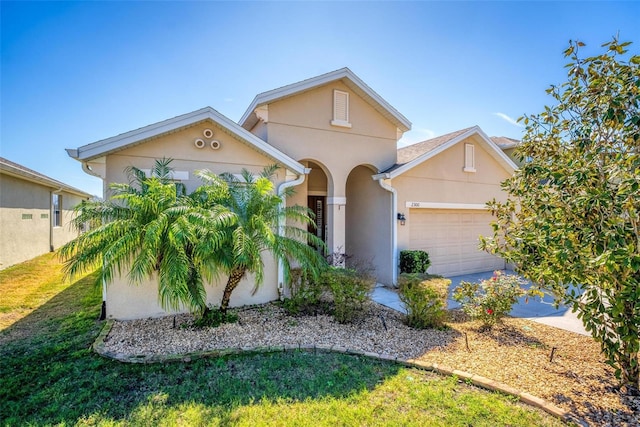 view of front of property with a front yard, an attached garage, and stucco siding