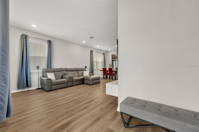 living area featuring light wood-style flooring, recessed lighting, visible vents, and baseboards