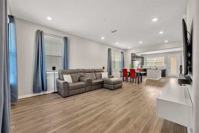 living area with recessed lighting, light wood-type flooring, baseboards, and visible vents