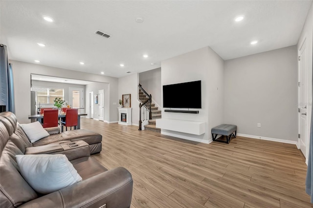 living area with light wood finished floors, visible vents, baseboards, stairs, and recessed lighting