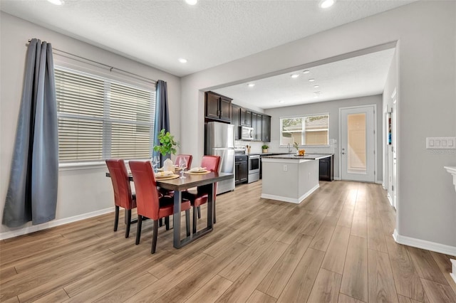 dining room featuring recessed lighting, baseboards, light wood-style floors, and a textured ceiling