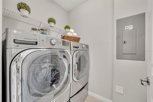 laundry area featuring baseboards, washer and clothes dryer, electric panel, laundry area, and light tile patterned flooring