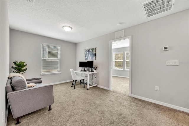 office area with visible vents, a textured ceiling, baseboards, and carpet