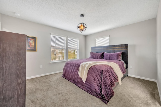 carpeted bedroom featuring a textured ceiling and baseboards