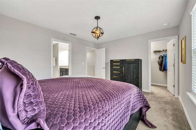 bedroom featuring visible vents, a walk in closet, baseboards, carpet flooring, and a textured ceiling