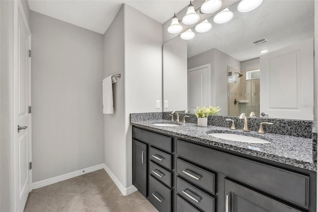 bathroom featuring double vanity, a shower stall, baseboards, and a sink