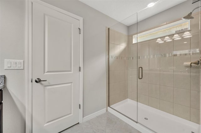 bathroom with baseboards, marble finish floor, and a shower stall