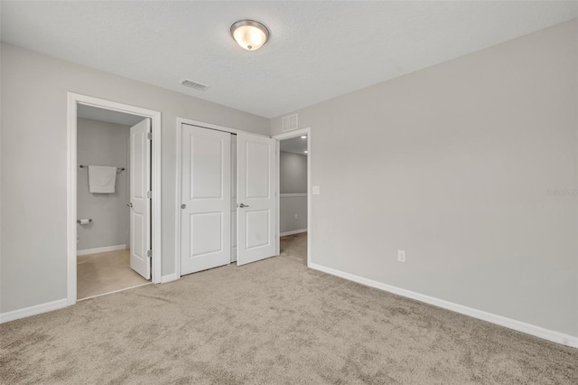 unfurnished bedroom featuring visible vents, carpet floors, baseboards, and ensuite bathroom