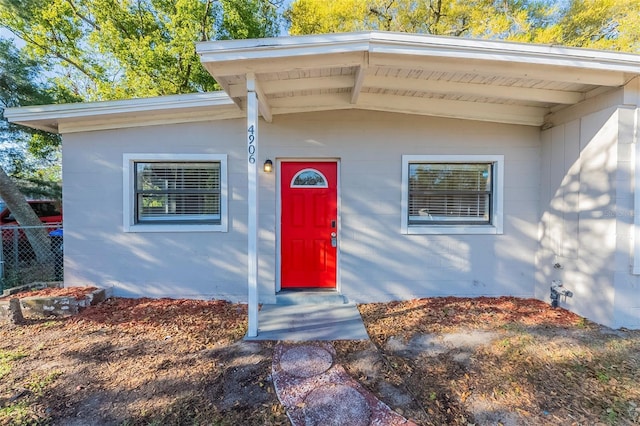 view of exterior entry featuring fence and concrete block siding
