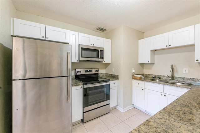 kitchen with white cabinetry, a sink, appliances with stainless steel finishes, visible vents, and stone counters