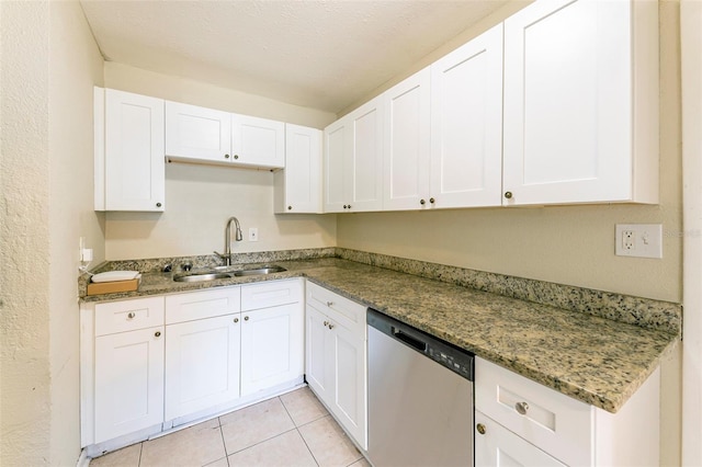 kitchen with a sink, light tile patterned floors, stone counters, stainless steel dishwasher, and white cabinets