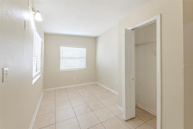 unfurnished bedroom with baseboards, light tile patterned floors, and a closet