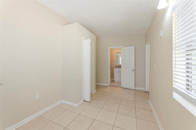 empty room featuring baseboards and light tile patterned floors