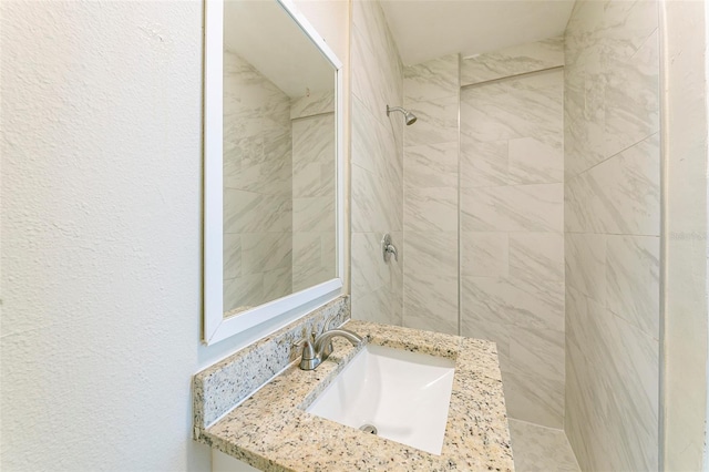 bathroom featuring a tile shower and a sink