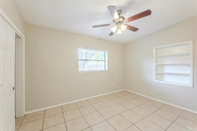 spare room featuring light tile patterned floors, ceiling fan, built in features, and baseboards