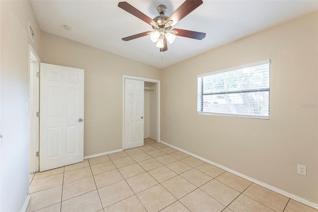 unfurnished bedroom featuring light tile patterned floors, a closet, baseboards, visible vents, and a ceiling fan