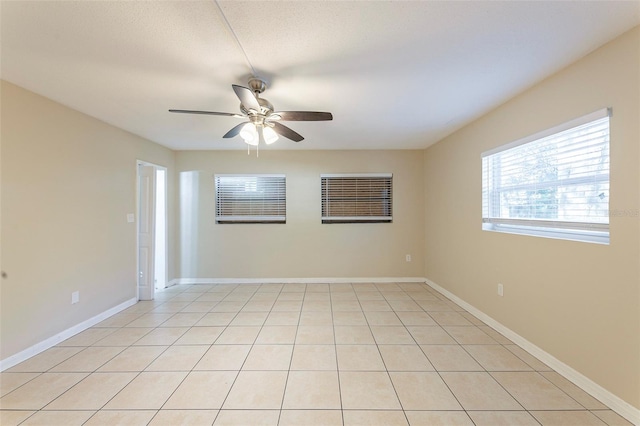 unfurnished room featuring baseboards, ceiling fan, and light tile patterned flooring