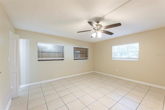 unfurnished room with light tile patterned floors, a ceiling fan, and baseboards