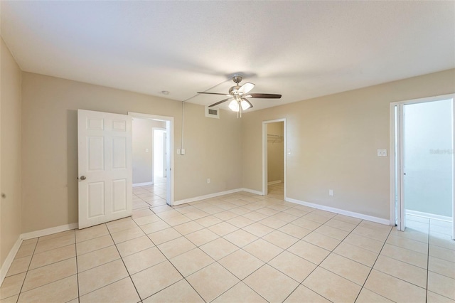 spare room featuring light tile patterned floors, ceiling fan, visible vents, and baseboards