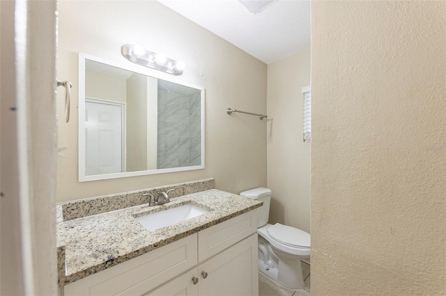 bathroom featuring vanity, toilet, a textured wall, and tile patterned flooring