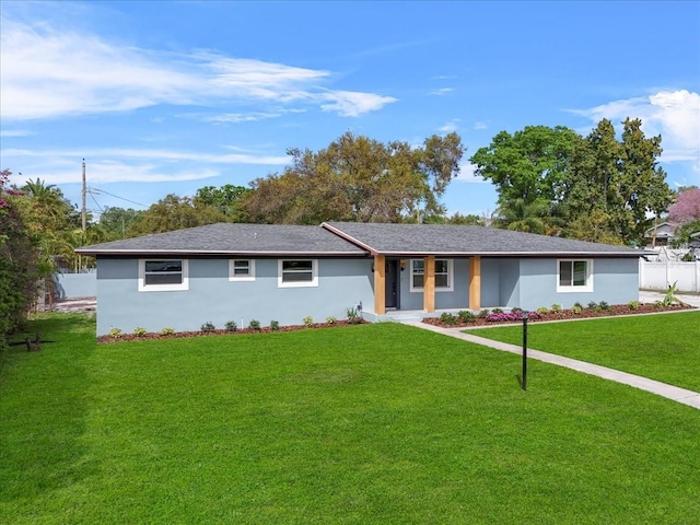 ranch-style house featuring a front yard, fence, and stucco siding