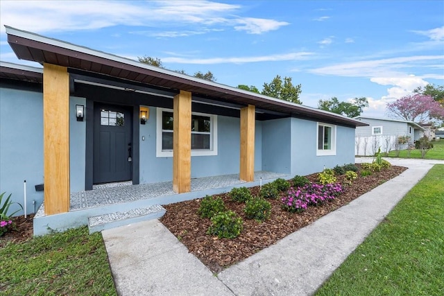 entrance to property with a porch and stucco siding