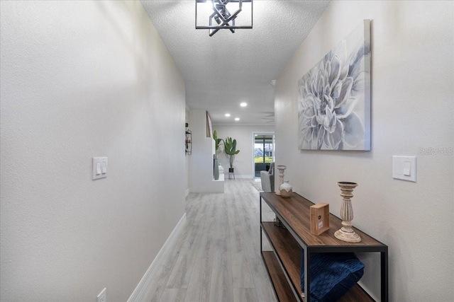 hallway with recessed lighting, baseboards, a textured ceiling, and light wood-style flooring