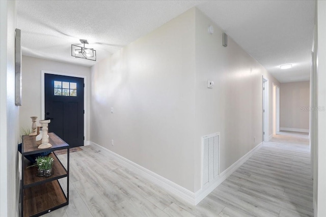 entrance foyer with baseboards, visible vents, a textured ceiling, and light wood-style floors