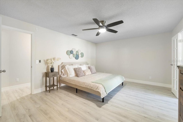 bedroom featuring visible vents, light wood-style flooring, a textured ceiling, and ceiling fan