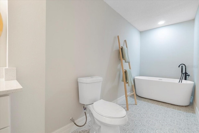 bathroom featuring a freestanding tub, baseboards, toilet, and a textured ceiling