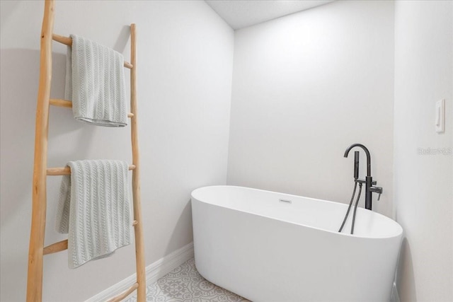 bathroom featuring tile patterned floors, a freestanding tub, and baseboards