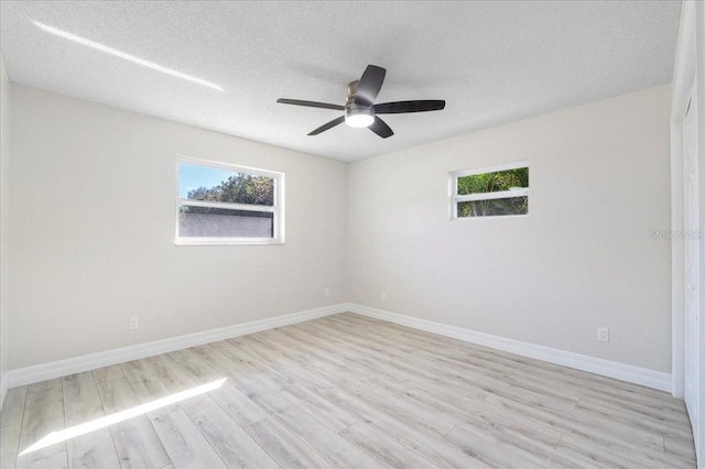 empty room with light wood-style flooring, a textured ceiling, baseboards, and a ceiling fan