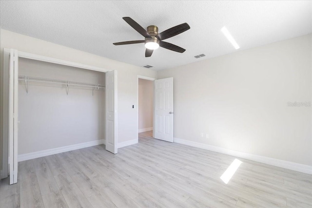 unfurnished bedroom featuring visible vents, baseboards, light wood-style flooring, a closet, and a textured ceiling