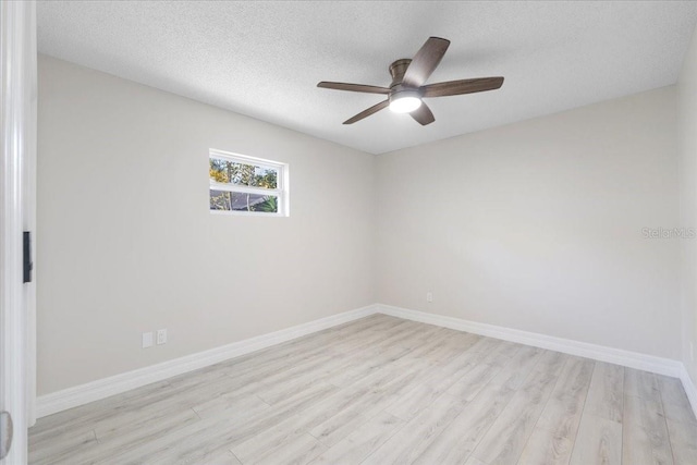 spare room featuring light wood finished floors, ceiling fan, a textured ceiling, and baseboards