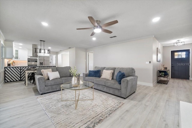 living area featuring crown molding, light wood-type flooring, and baseboards