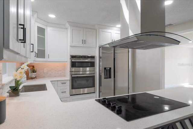 kitchen featuring glass insert cabinets, double oven, island exhaust hood, white cabinetry, and black electric cooktop