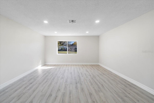 spare room featuring visible vents, a textured ceiling, recessed lighting, light wood finished floors, and baseboards