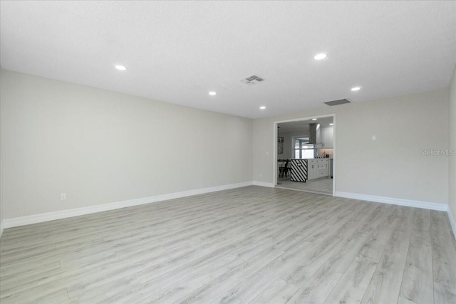 empty room with recessed lighting, baseboards, visible vents, and light wood finished floors