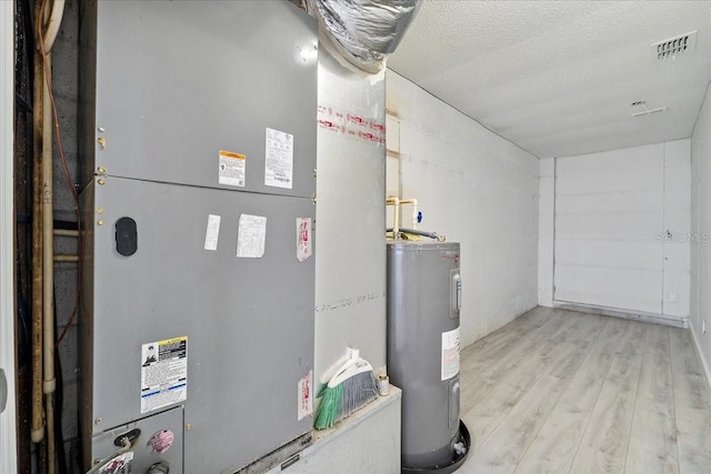 utility room with visible vents, heating unit, and electric water heater