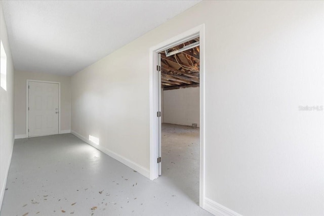 hall with baseboards and concrete flooring