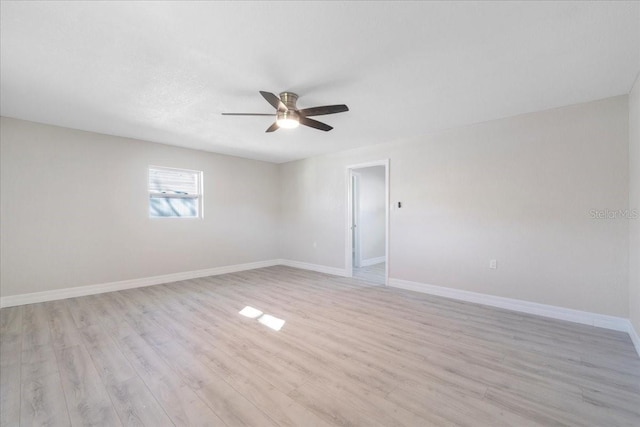 spare room featuring ceiling fan, light wood-type flooring, and baseboards