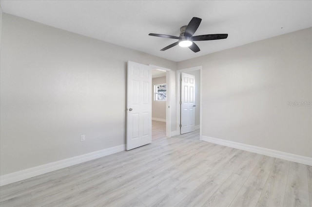 empty room featuring light wood-type flooring, baseboards, and a ceiling fan