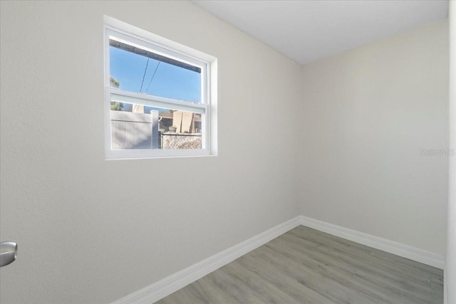 unfurnished room with baseboards and wood finished floors