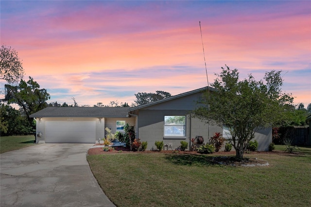 view of front of home featuring a front lawn, concrete block siding, a garage, and driveway