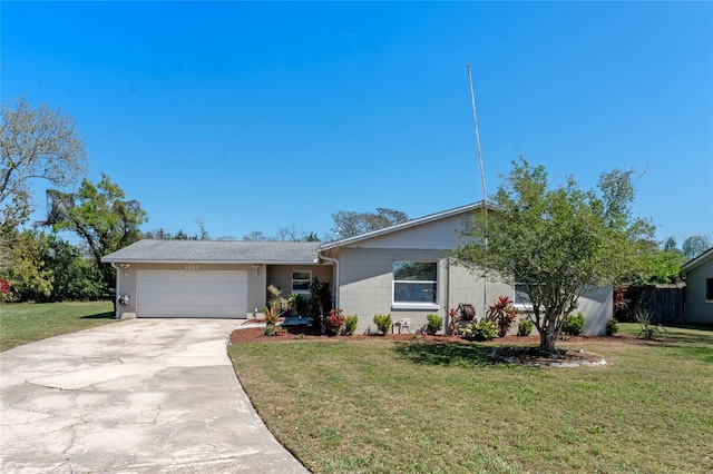 ranch-style home with an attached garage, concrete block siding, a front yard, and concrete driveway