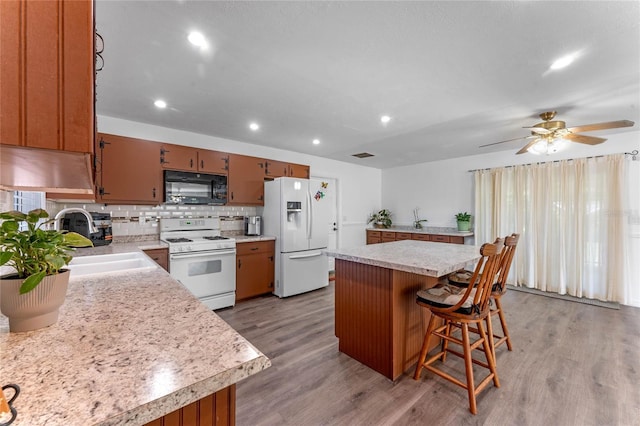 1021 Mare Bello Dr, Winter Park, FL 32792 - kitchen with decorative backsplash, white appliances, light wood-type flooring, light countertops, and a sink