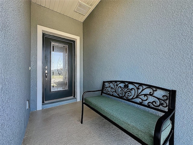 entrance to property with visible vents and stucco siding