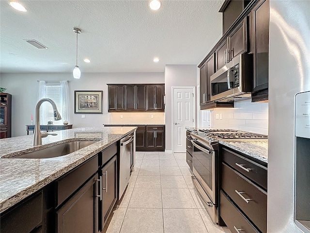 kitchen with visible vents, a sink, light stone counters, appliances with stainless steel finishes, and light tile patterned floors