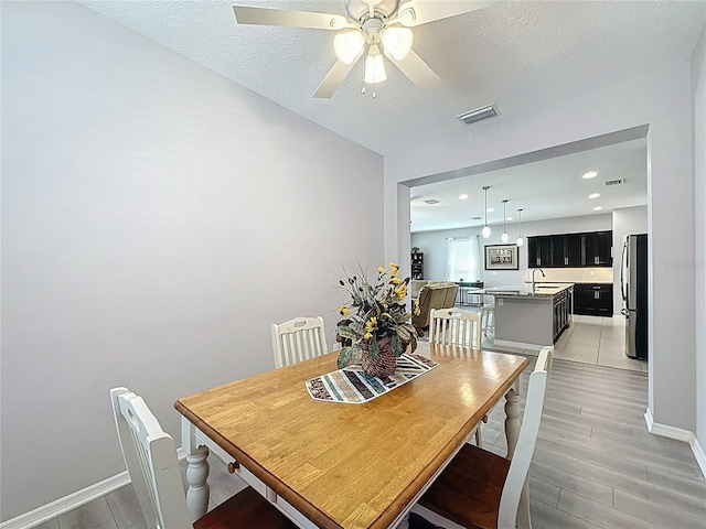 dining room featuring baseboards, visible vents, light wood finished floors, and ceiling fan