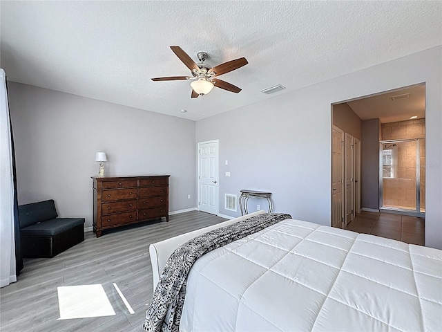 bedroom featuring wood finished floors, a ceiling fan, visible vents, and a textured ceiling